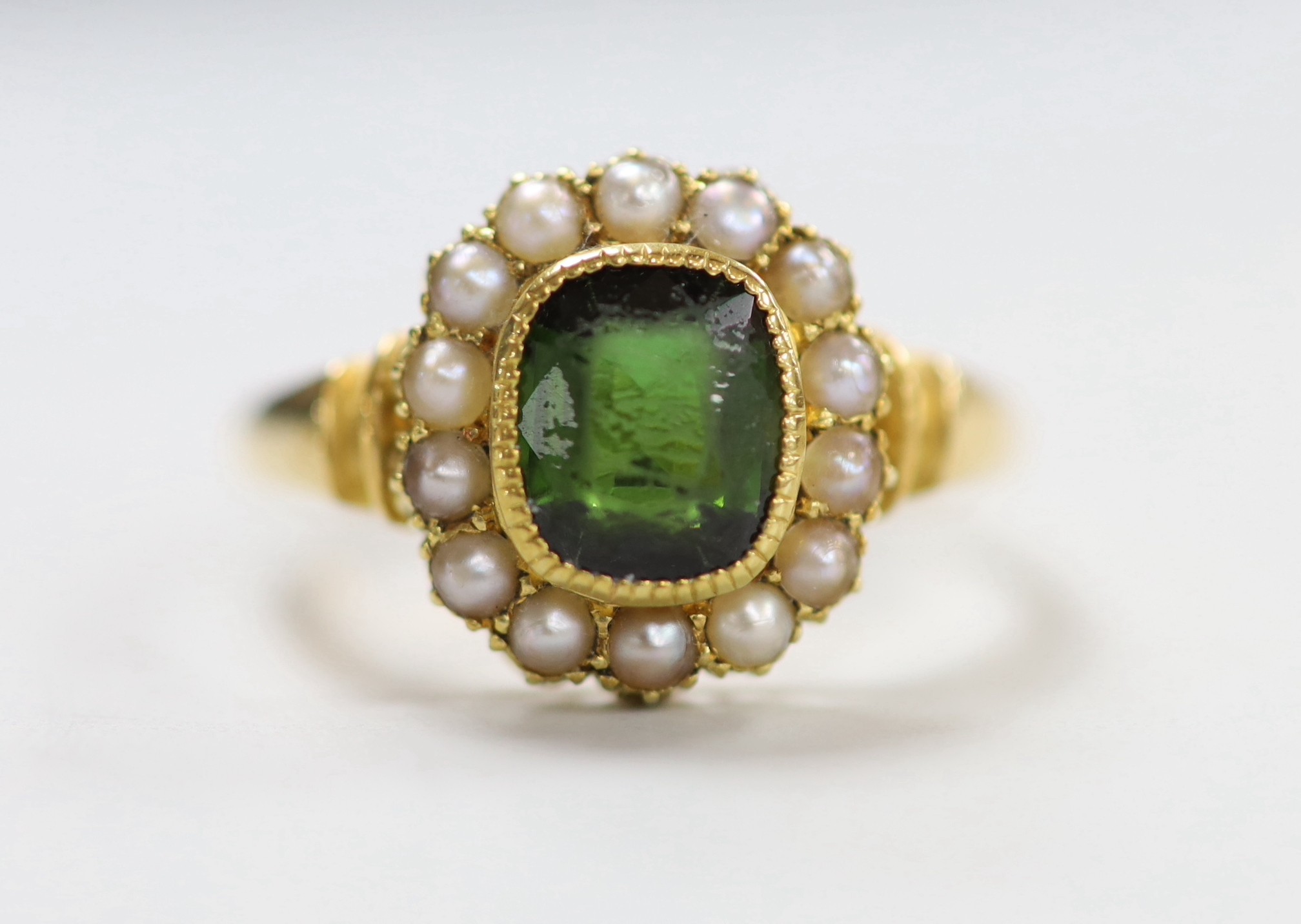 An Edwardian 18ct gold, green tourmaline and split pearl set oval cluster ring, size S, gross weight 6 grams.